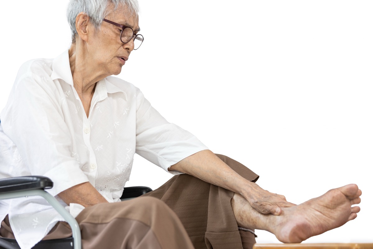Elderly person examining painful foot